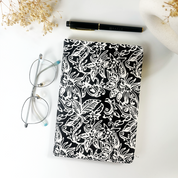 Black and white batik notebook with floral motif styled beside glasses and pen on white desk — Batik Boutique handmade stationery.