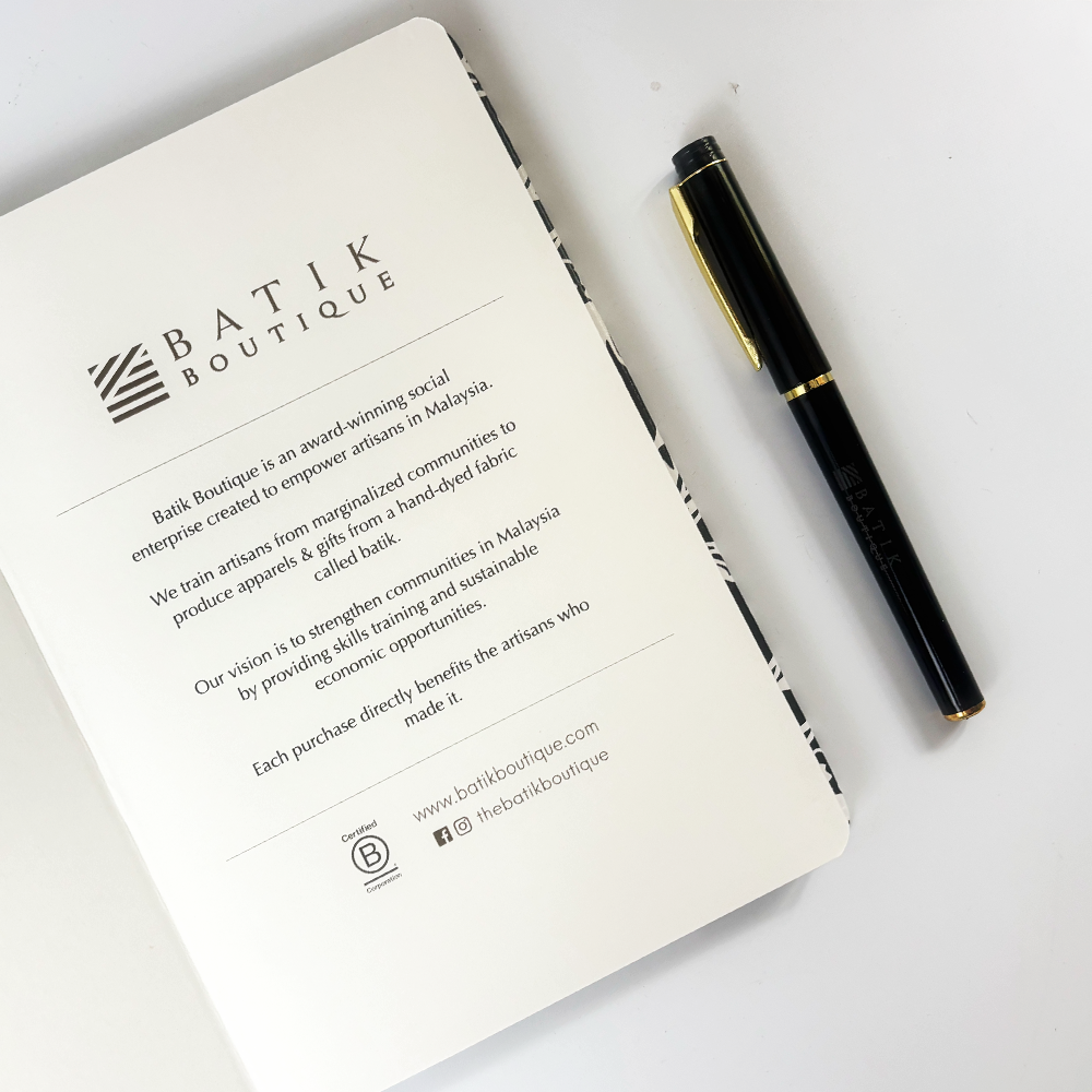 Inside cover of Batik Boutique notebook with brand story and mission statement, paired with black and gold pen.