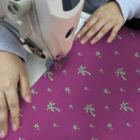 an artisan in the middle of sewing the batik fabric fuchsia palm