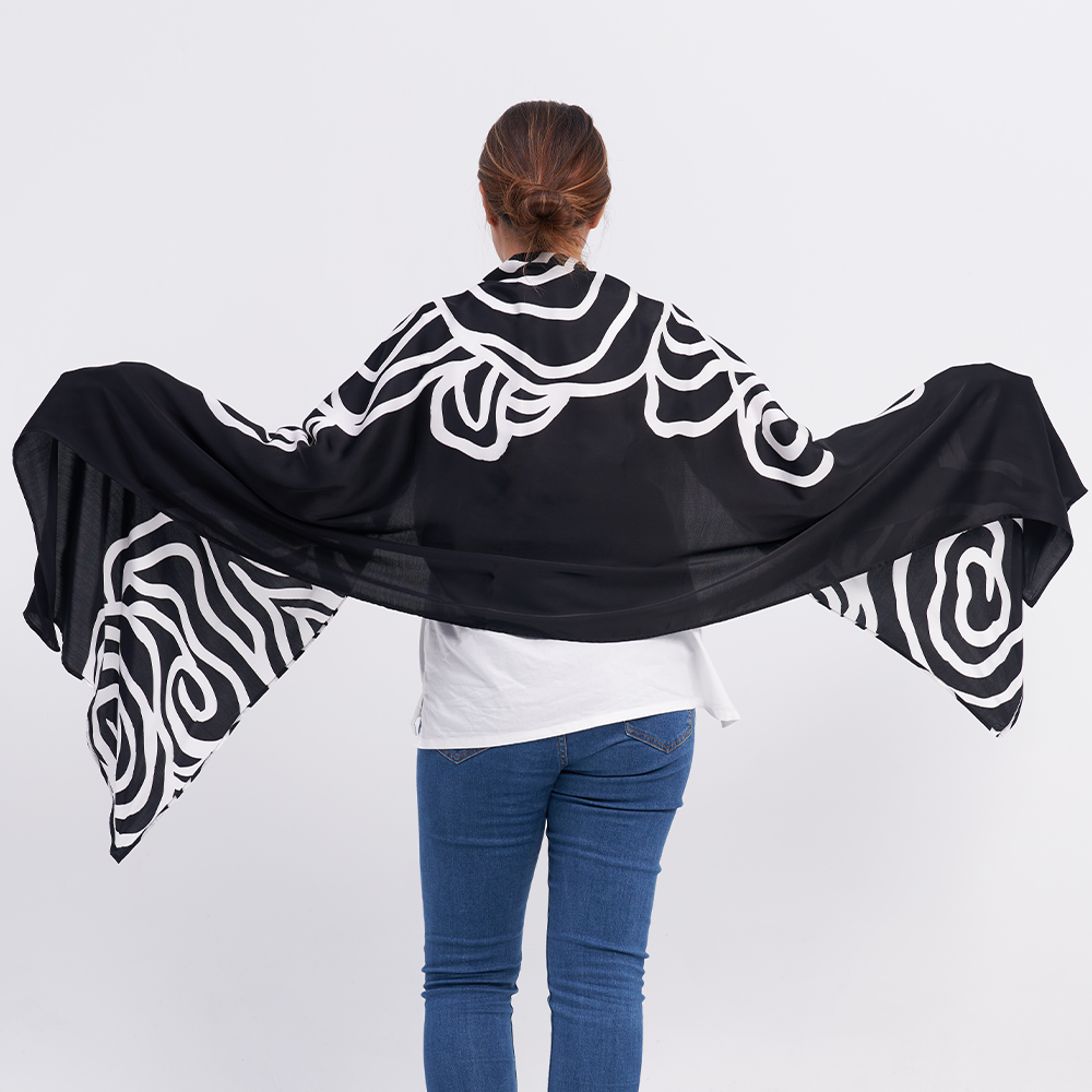a woman posing with her back to the camera to show the details on the back of the batik scarf in the pattern black kerepek