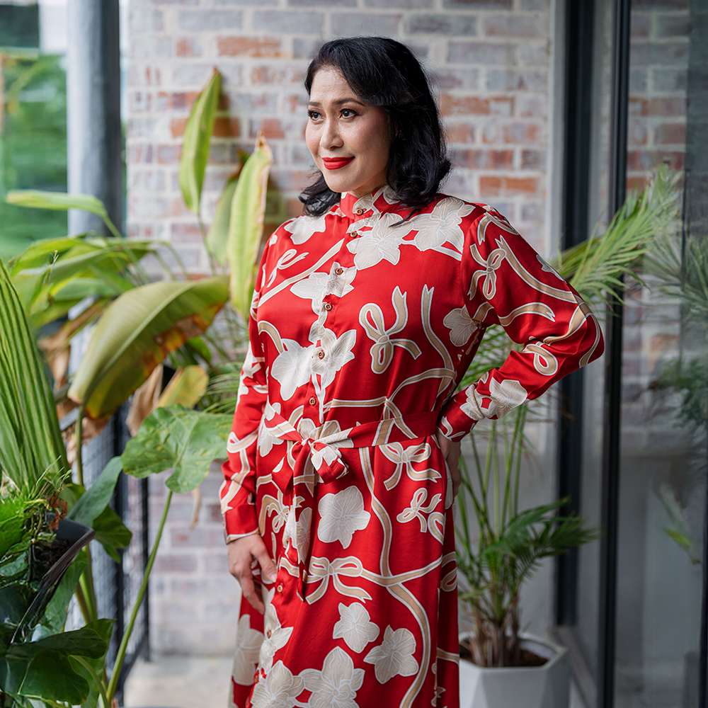 a woman poses in batik long shirt dress in the pattern ruby fleur in a lifestyle photo