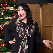 a woman wearing a black rimba scarf in a festive background