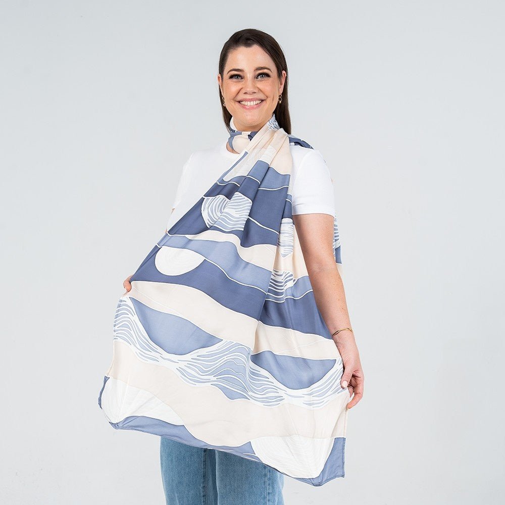 Woman wearing a large blue and white patterned scarf on a plain background