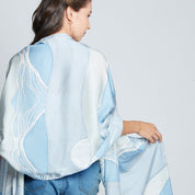 Full view of a woman wearing a white shirt and blue batik cotton silk scarf in print that was hand-painted by artisans of Batik Boutique. 