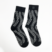 a batik inspired socks in the pattern black snakeskin against a white background
