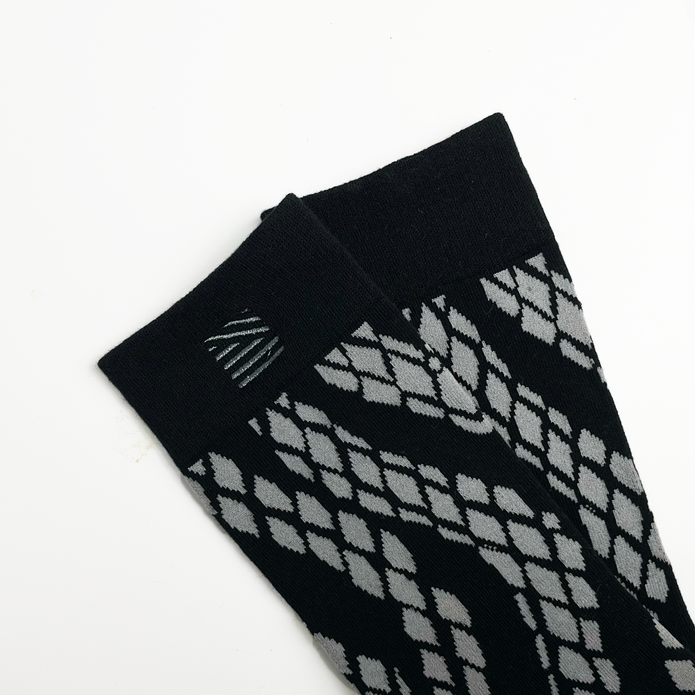 a closeup of black snakeskin socks with batik boutique's logo embroidered