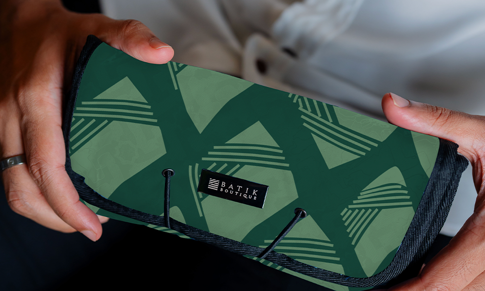 a model holding an authentic batik travel roll-up pouch in the pattern green nasi lemak