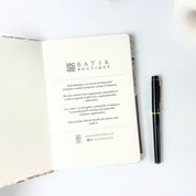 Taupe Petola notebook being displayed open with pen beside 