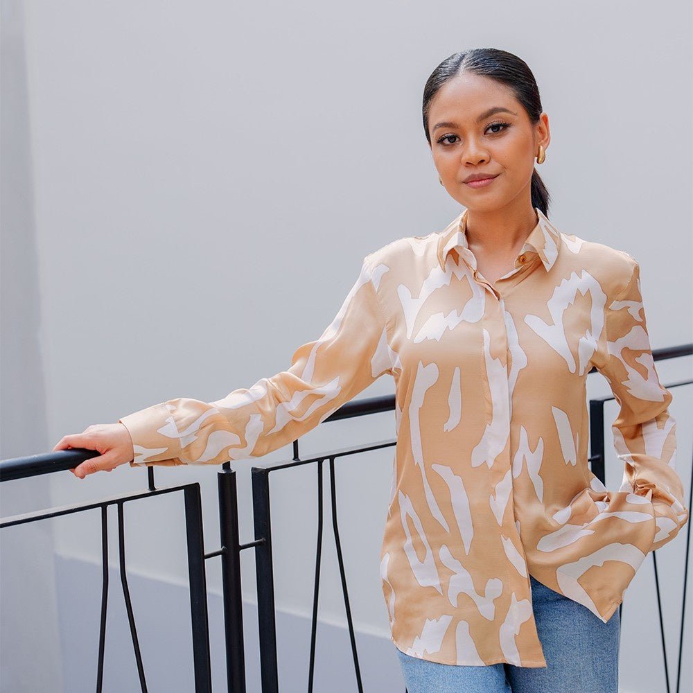 Woman styling a Tan Rimba batik shirt in an urban setting, highlighting the versatile fit and modern jungle-inspired design