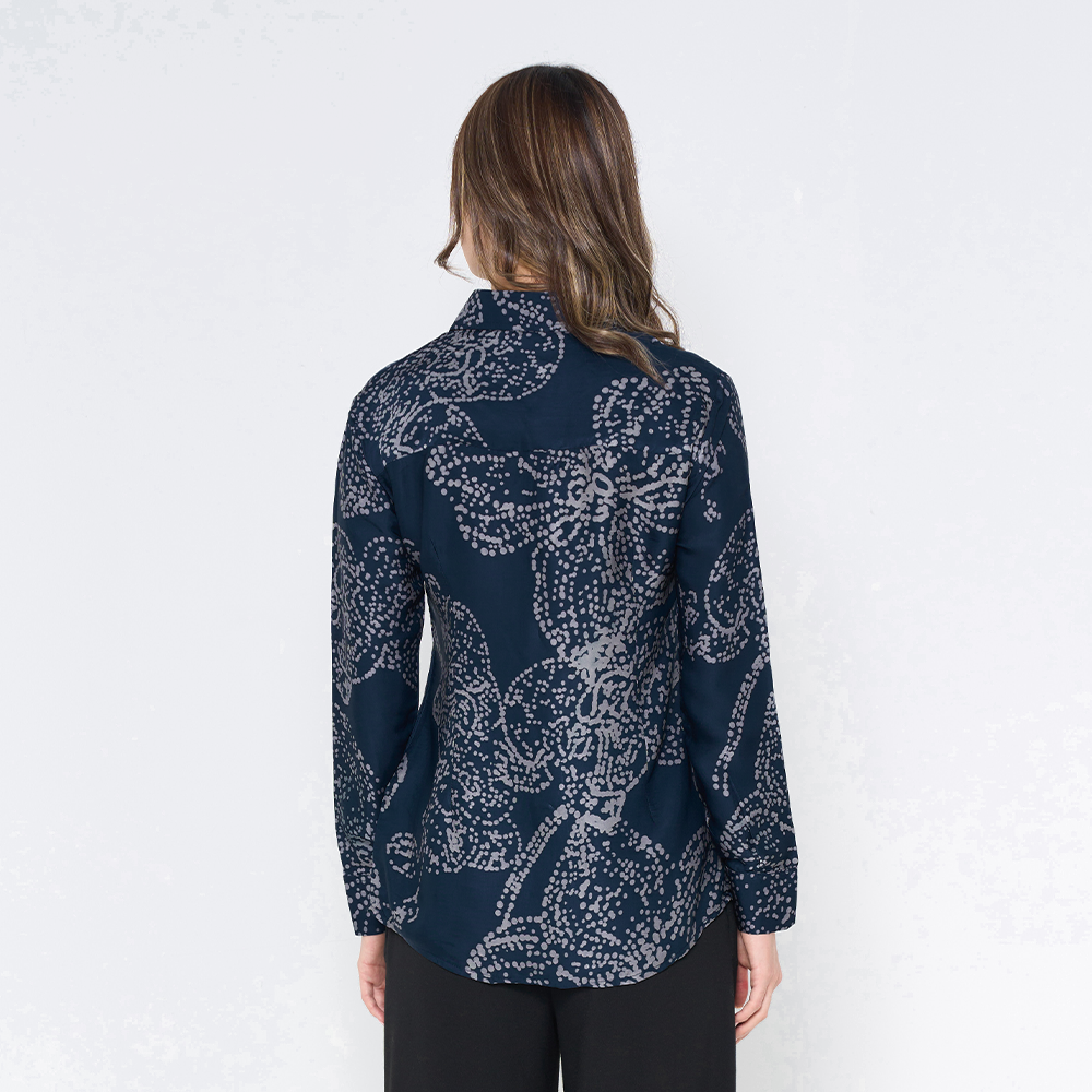 a woman in a batik shirt against a white background in the pattern navy orchid