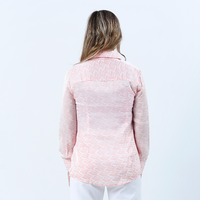 a model posing with her back to the camera while posing against a neutral background in a peach bloom shirt