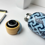 Blue patterned water bottle and wooden container on a white surface