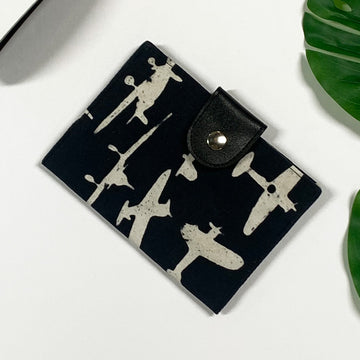 a lifestyle photo of a passport cover made of batik in the pattern black airplane