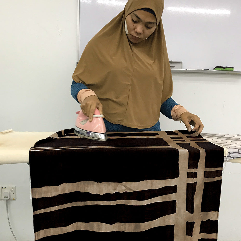 a seamstress ironing black ecru fabric