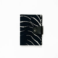 A whitebox photo of passport cover in black fern pattern showing outside and front side of the passport cover