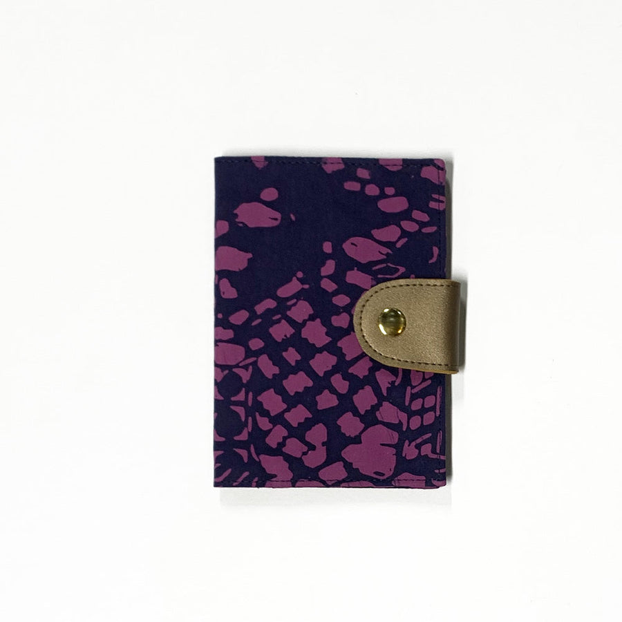 a front view of a passport cover made of batik against a neutral background in the pattern purple bintik