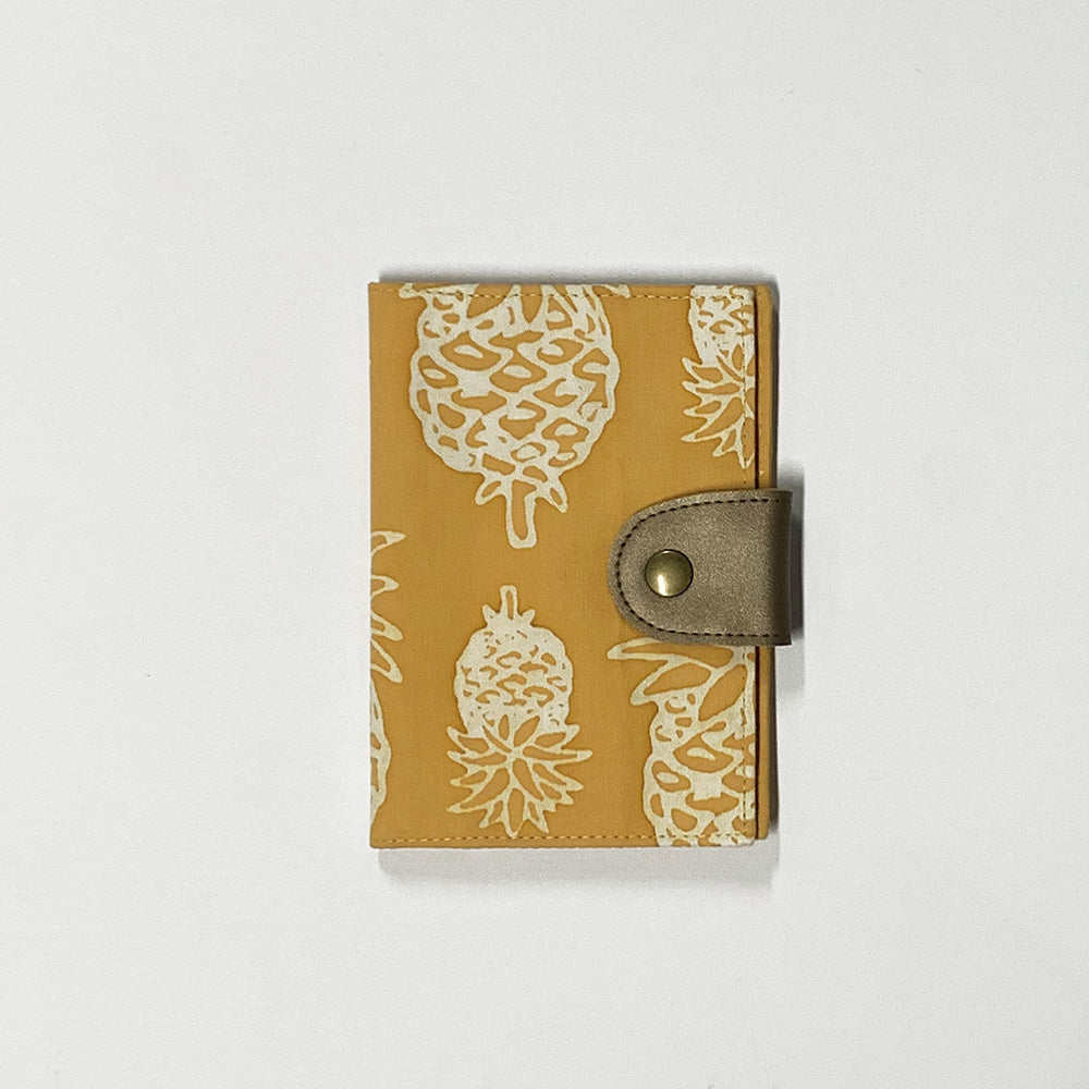 the front view of a passport cover made of batik in the pattern golden pineapple