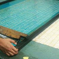 A photo of an artisan in the middle of creating batik through the intricate silkscreening process