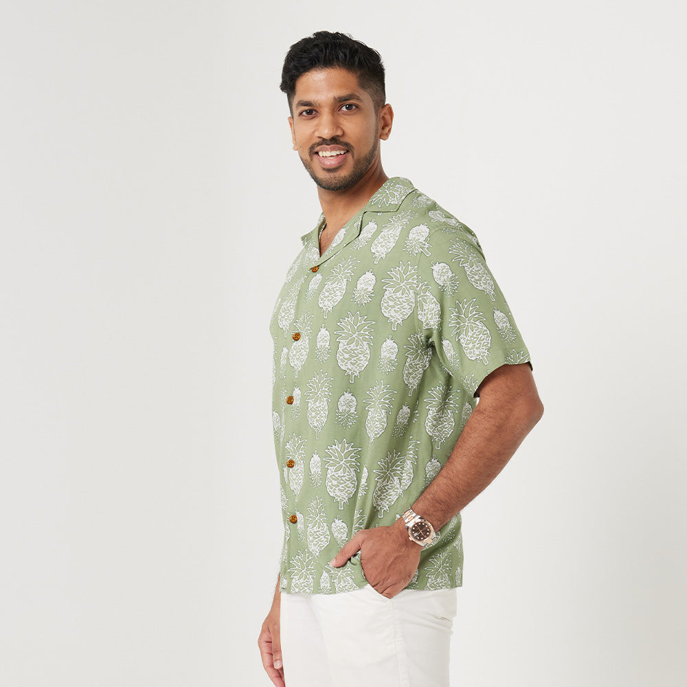 a man standing in front of white background styling batik cuban shirt in olive pineapple pattern 