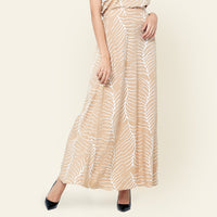 a photo of woman standing in front of beige background styling batik skirt in latte fern print