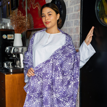 a woman posing with a batik scarf in the pattern purple bintik in a lifestyle