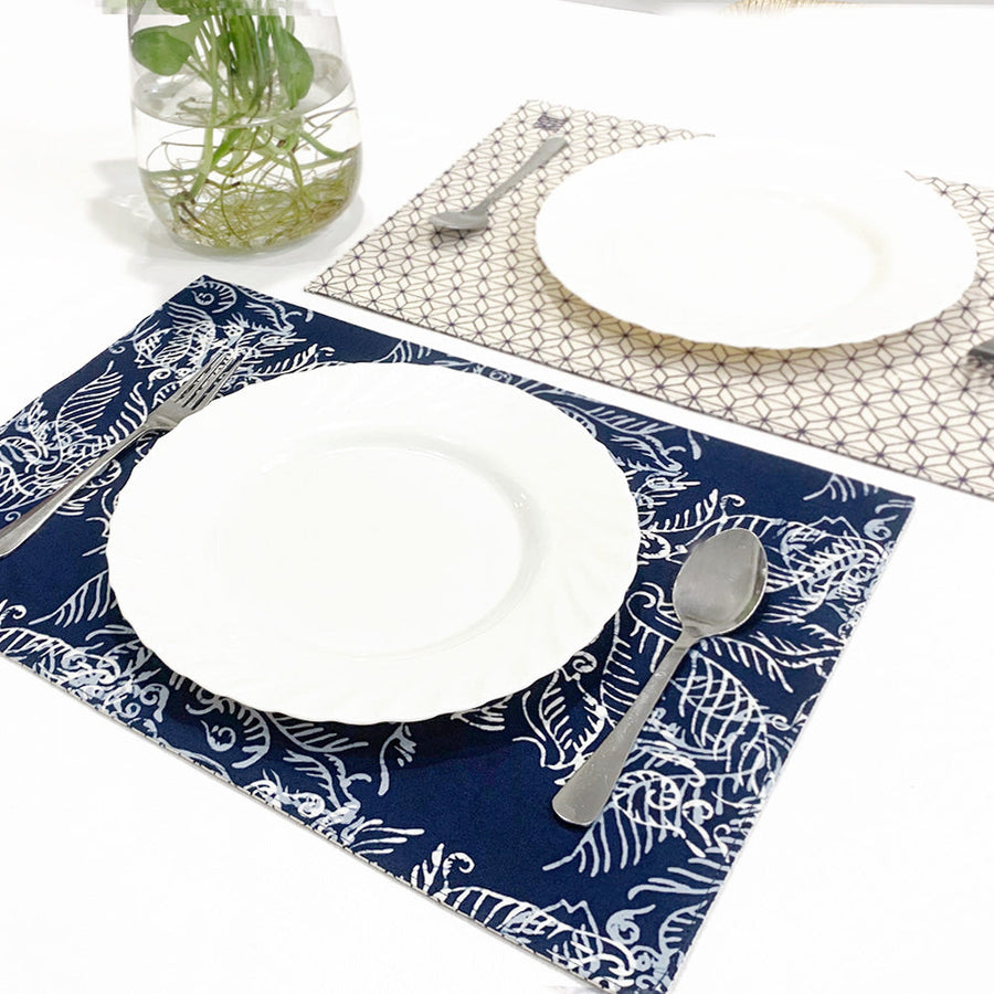 a lifestyle photo of reversible batik placemat in blue nautical fern pattern on dining table complete with plates and cutlery