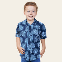 A young boy stands confidently in front of a neutral background, showcasing his authentic batik shirt designed for boys