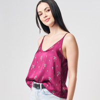 a model posing on a white background in a batik camisole in the print fuchsia palm with jeans