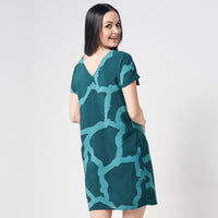 A woman elegantly presenting a reversible batik dress adorned with the enchanting Forest Chain pattern, set against a neutral background, showcasing the versatile and stylish design