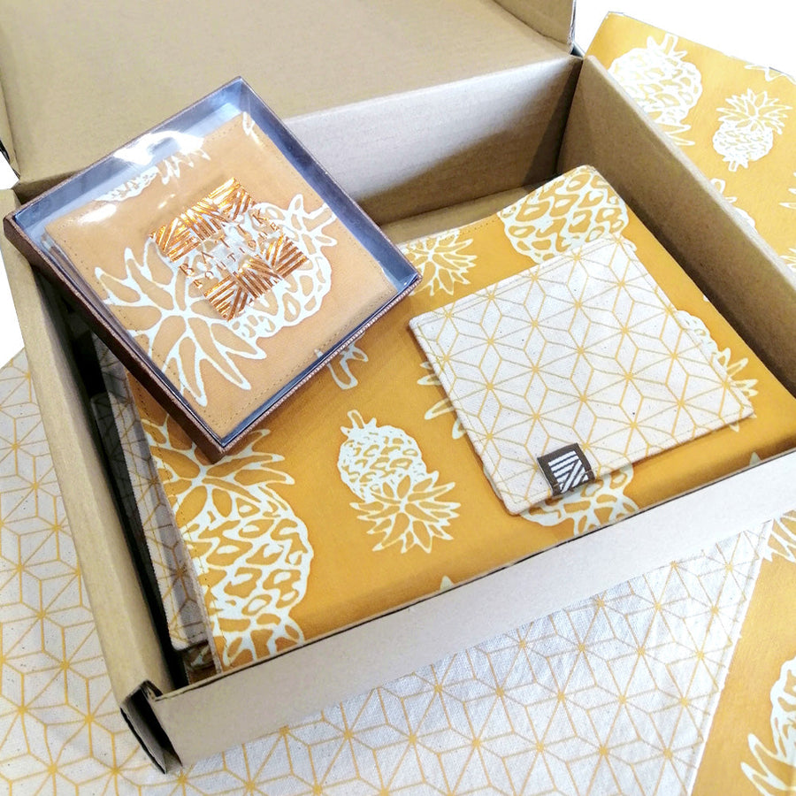 a photo of homeware gift set made of batik in the pattern golden pineapple with reversible placemats and coasters