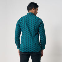 A man confidently facing away from the camera, allowing for a showcase of the exquisite details on the back of his authentic Forest Firework patterned batik shirt