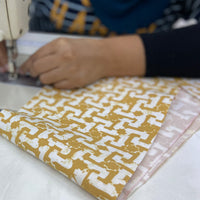 An artisan skillfully sewing authentic batik fabric in the selected pattern