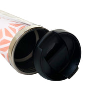 a batik tumbler with its lid open laying on a white surface with peach firework design on it