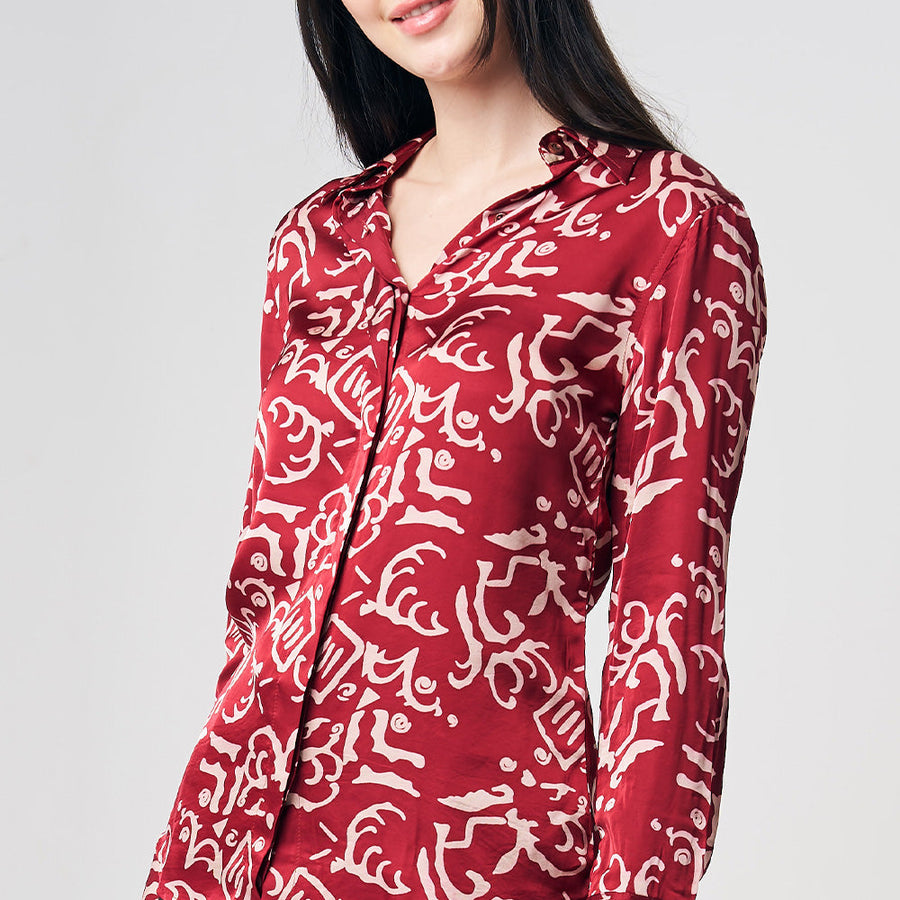 A woman gracefully donning a batik shirt featuring the Crimson Diwanie pattern, presented against a neutral background, showcasing the elegance and vibrancy of the design