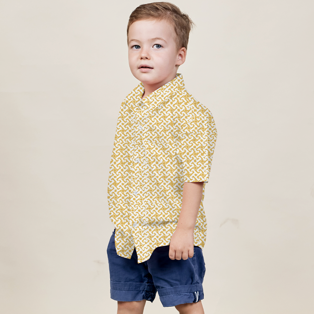 A young boy striking a confident pose against a neutral backdrop, dressed in a Mustard Arabesque patterned batik shirt