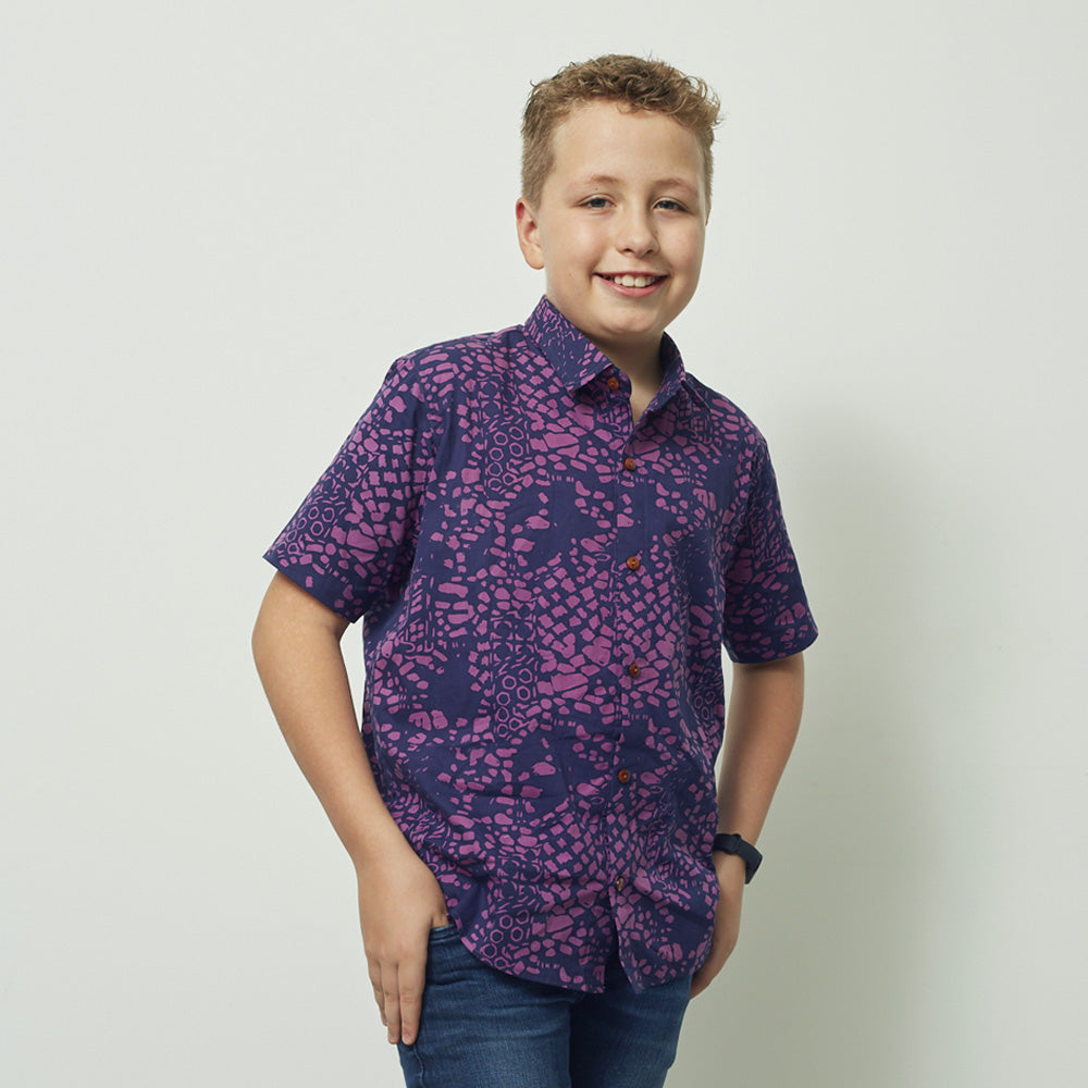 A boy wearing batik shirt in purple bintik pattern