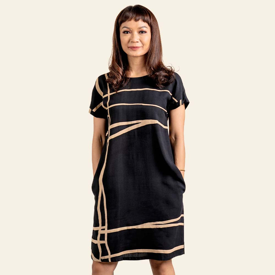 a photo of a model standing against a neutral background in a batik dress in the pattern black ecru