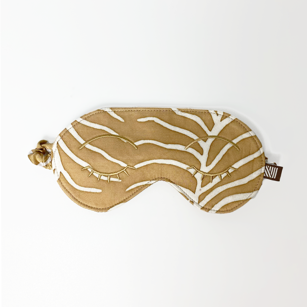 an eye mask against a white background made of batik in the pattern latte fern