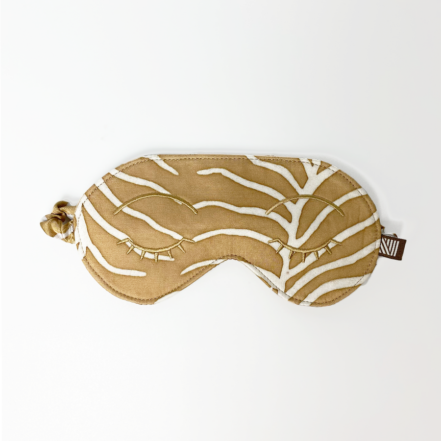 an eye mask against a white background made of batik in the pattern latte fern