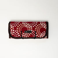 A whitebox photo of batik roll-up travel pouch in red crimson lunar pattern.  Showing front side of the bag complete with silver tag with Batik Boutique logo