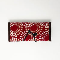Whitebox photo of a red Crimson Lunar patterned batik roll-up travel pouch, displaying the back side with an attached string lock for secure closure.