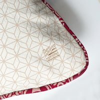 A close up photo of crimson celestial pillow cover showing embroided batik boutique logo