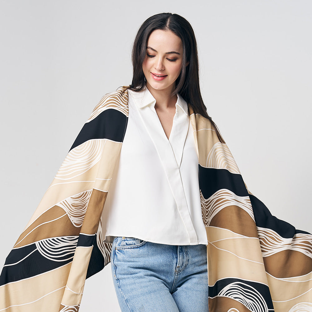 a women is styling handpainted batik scarf while standing in front of white background