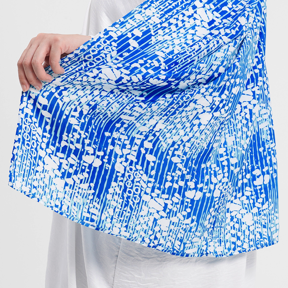 a closeup shot of a batik scarf in the pattern blue bintik against a neutral background
