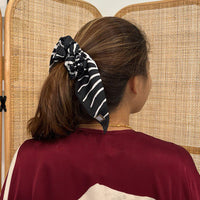 a woman wearing batik scrunchies against a rattan backdrop in the pattern black fern