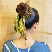 A woman is wearing batik headband in Olive Fern pattern made by remanant batik fabric for more sustainable approach