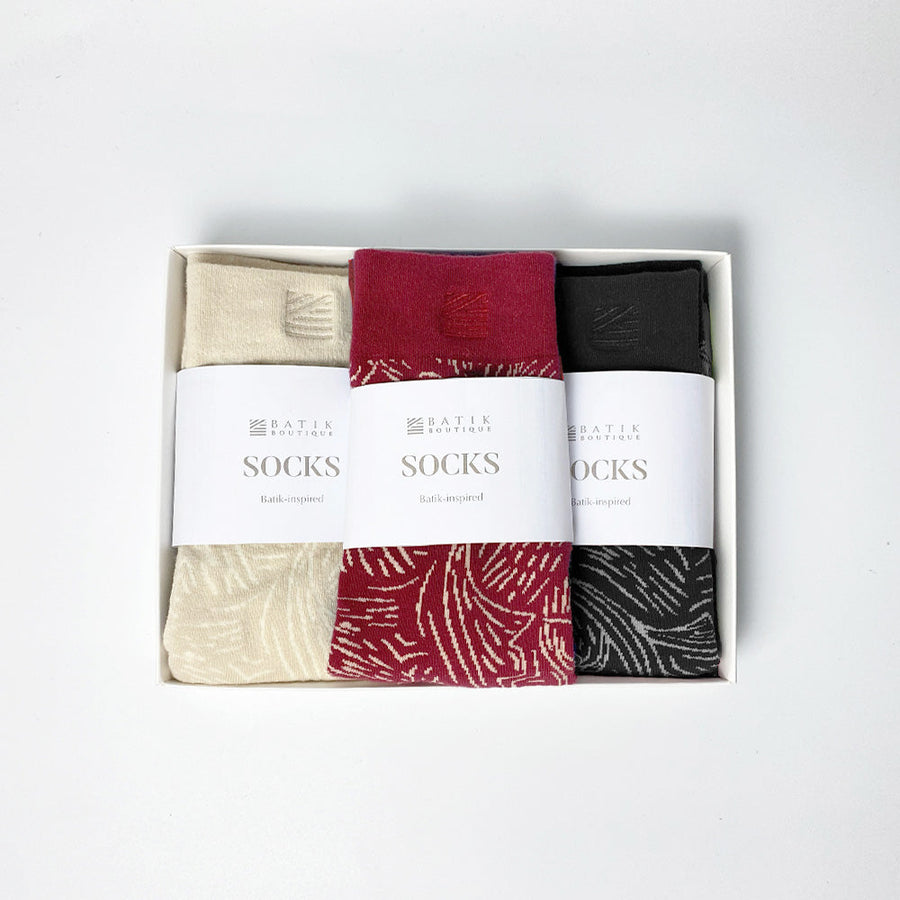 A photo of batik-inspired socks gift set in driftwood pattern. Comes in a sleeve and in a white box ready for gifting. Include 3 color which is red, black and beige color.