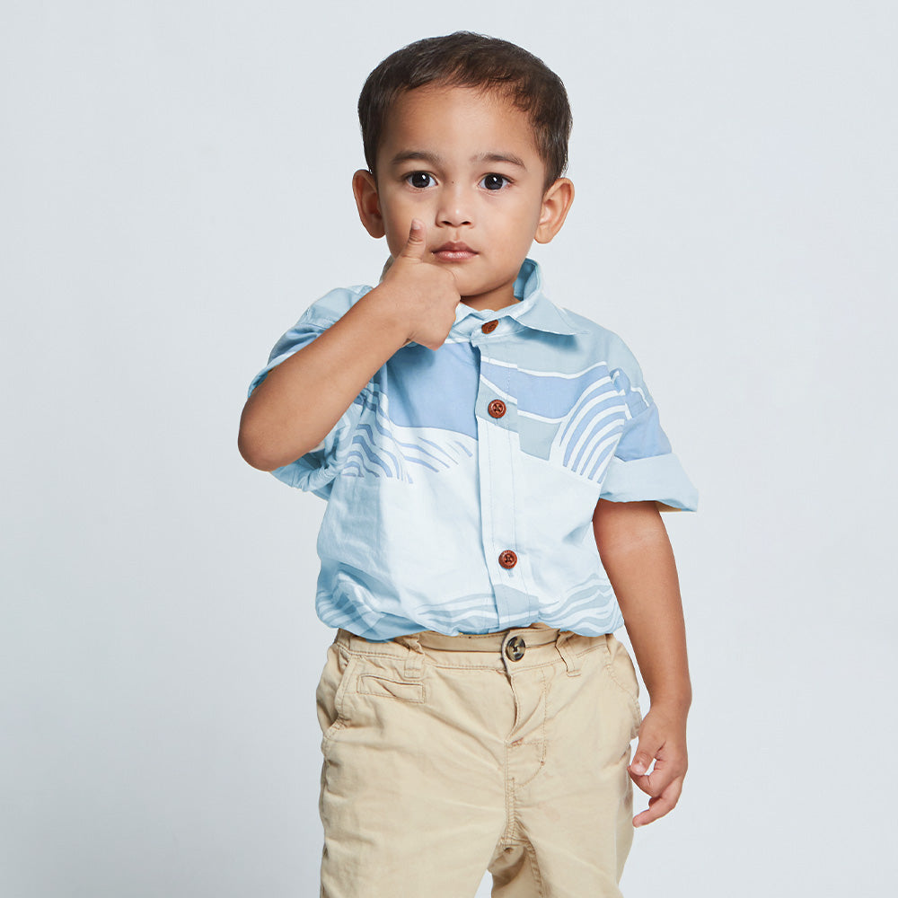 Young boy wearing blue batik shirt with wooden buttons.