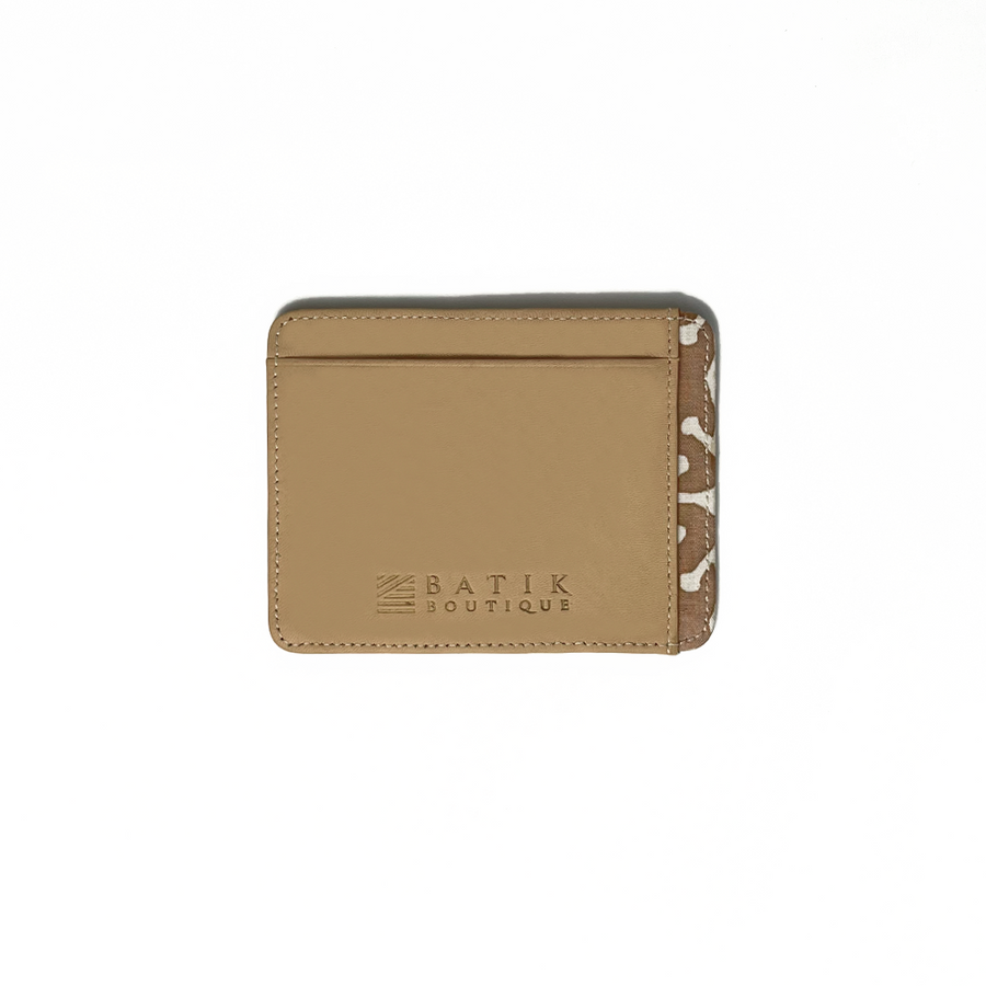 A whitebox photo of card case in genuine beige leather with a touch of batik fabric at the side in latte kompas pattern. With Batik Boutique logo engraved