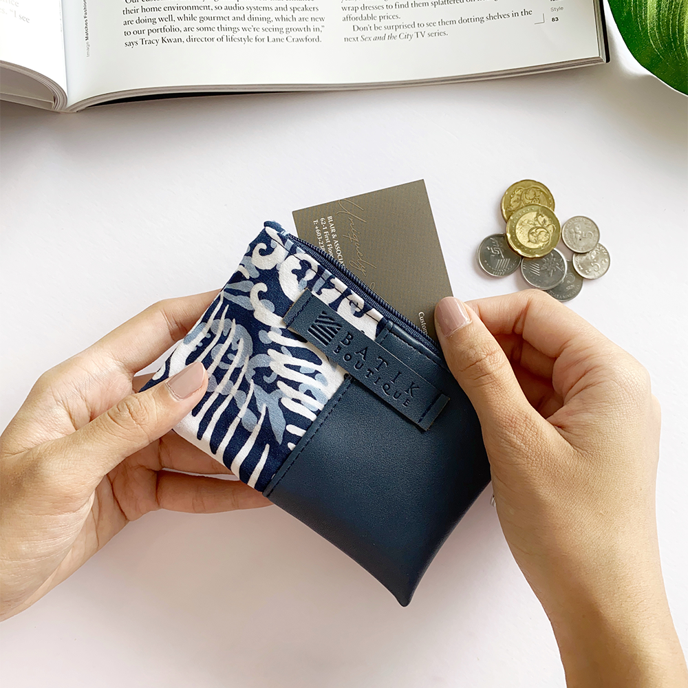 a lifestyle photo of a card holder made of batik in the pattern blue nautical fern with props accompanying it